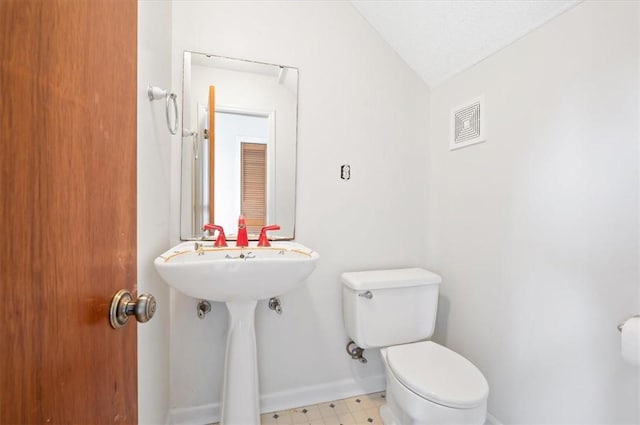 bathroom with toilet, baseboards, visible vents, tile patterned floors, and vaulted ceiling