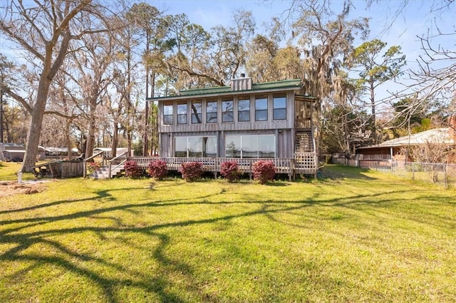 rear view of house featuring a yard, fence, and a wooden deck