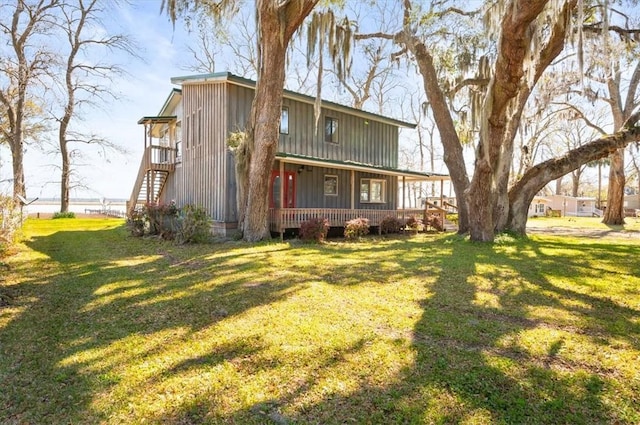 rear view of property with covered porch, board and batten siding, and a lawn