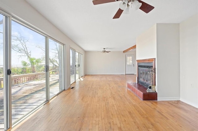 unfurnished living room with light wood finished floors, baseboards, a ceiling fan, and a tile fireplace