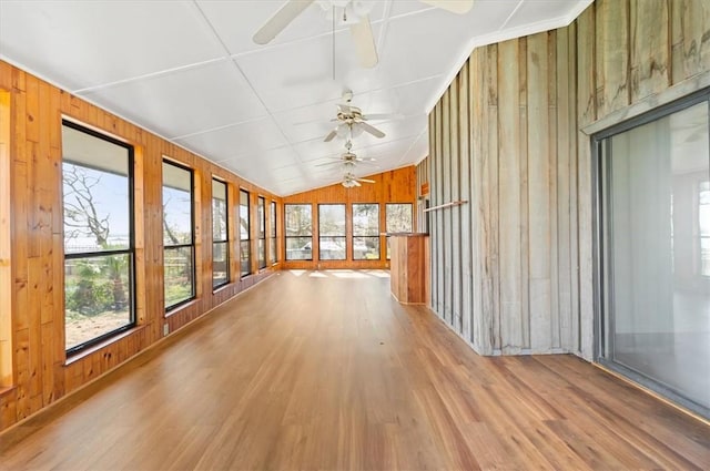 unfurnished sunroom with vaulted ceiling, wood walls, and wood finished floors