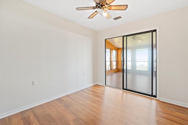 empty room featuring baseboards, visible vents, and wood finished floors