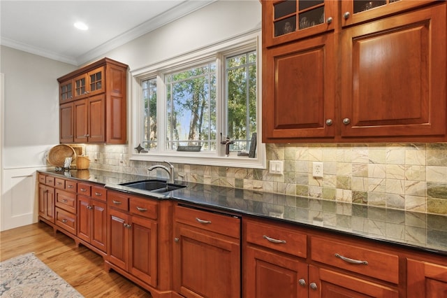 kitchen featuring ornamental molding, light hardwood / wood-style flooring, dark stone counters, and sink