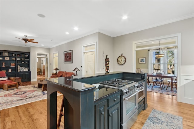 kitchen with light wood-type flooring, ceiling fan, crown molding, stainless steel stove, and a kitchen island