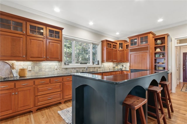 kitchen featuring a kitchen breakfast bar, crown molding, paneled built in refrigerator, light wood-type flooring, and a kitchen island