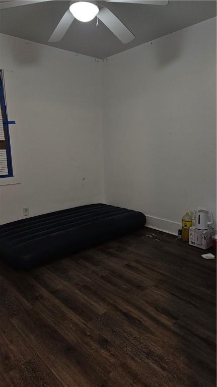 spare room featuring baseboards, a ceiling fan, and dark wood-type flooring
