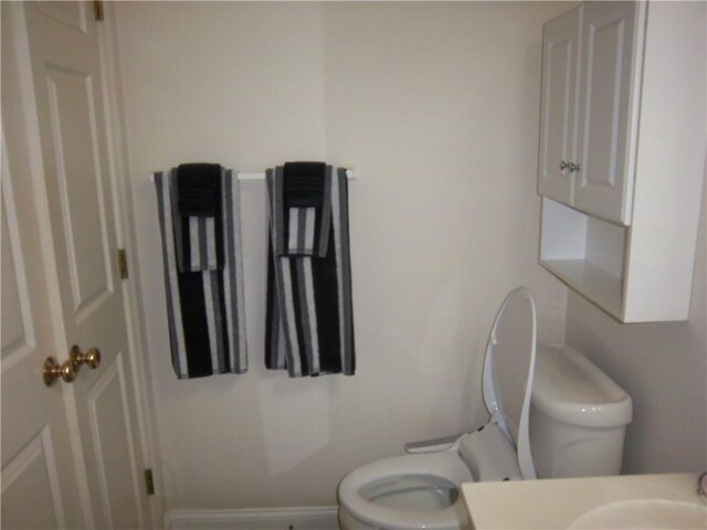 bathroom with toilet, vanity, and baseboards
