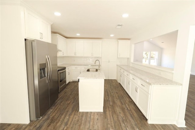 kitchen with light stone countertops, white cabinetry, sink, stainless steel appliances, and kitchen peninsula