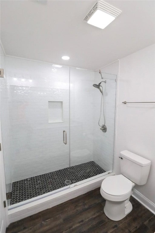 bathroom featuring toilet, wood-type flooring, and a shower with door