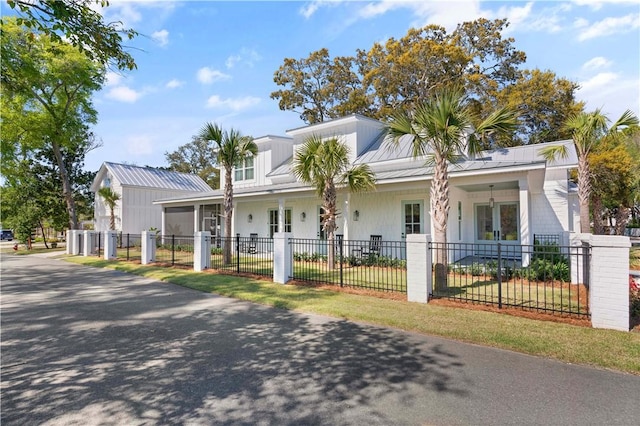 view of front of home with a fenced front yard, covered porch, and metal roof