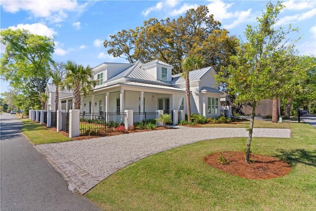 view of front facade featuring a standing seam roof, a front lawn, a fenced front yard, and metal roof