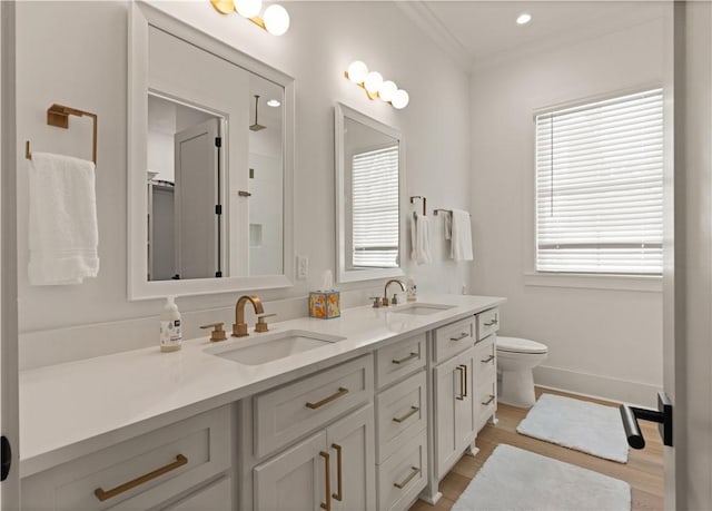 full bathroom with toilet, ornamental molding, a sink, wood finished floors, and double vanity