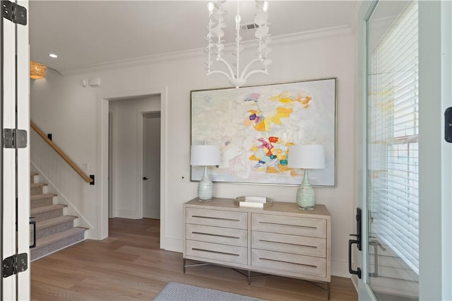 hallway featuring stairs, light wood-style flooring, baseboards, and ornamental molding