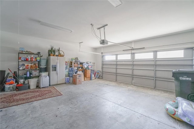 garage featuring white refrigerator with ice dispenser and a garage door opener