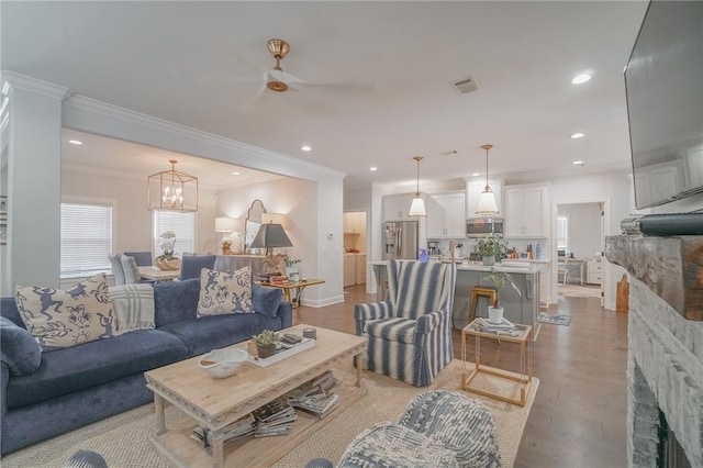 living room featuring ceiling fan with notable chandelier, light hardwood / wood-style flooring, and ornamental molding