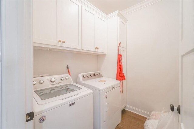 laundry area featuring washer and dryer, cabinets, ornamental molding, and light hardwood / wood-style flooring