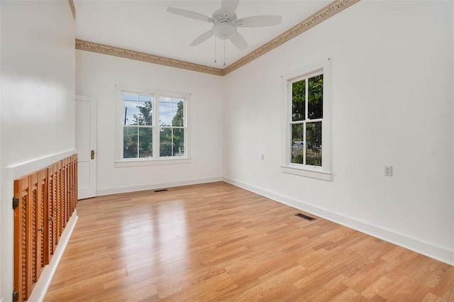spare room with plenty of natural light, light wood-type flooring, a ceiling fan, ornamental molding, and baseboards