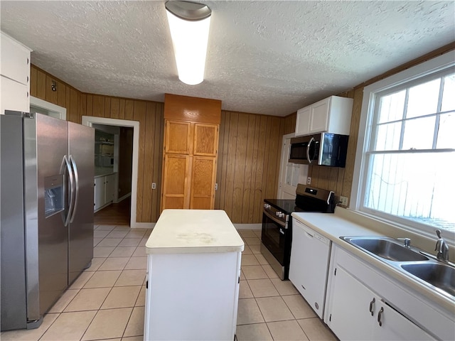 1601 Macon Ave, Brunswick, GA 31520 - kitchen with stainless steel appliances, a center island, wooden walls, white cabinetry, and light countertops