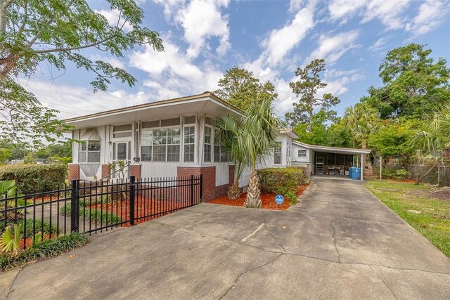 manufactured / mobile home with brick siding, concrete driveway, a carport, and a sunroom