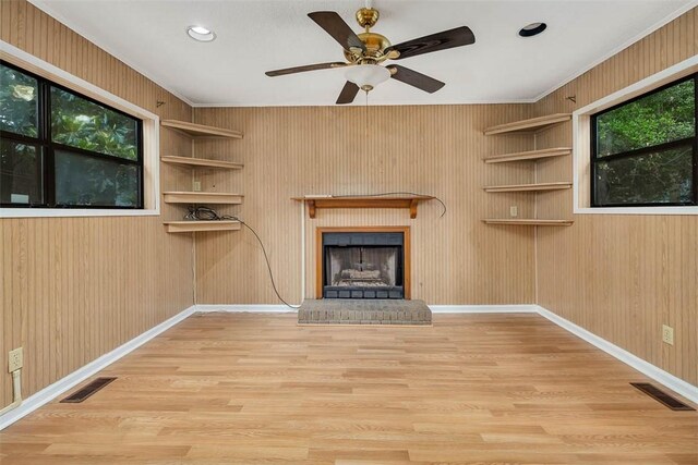 unfurnished living room featuring wood finished floors, a brick fireplace, baseboards, a ceiling fan, and crown molding