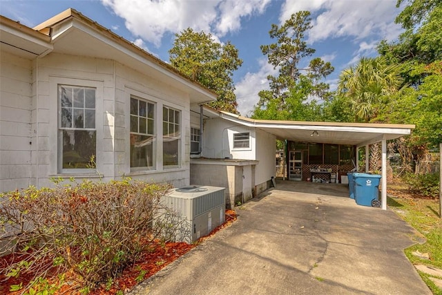 view of home's exterior featuring central air condition unit, concrete driveway, and a carport