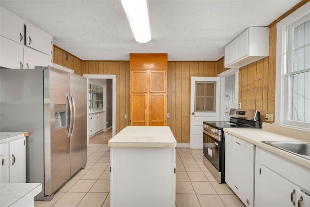 kitchen featuring appliances with stainless steel finishes, a center island, a textured ceiling, light tile patterned floors, and a sink