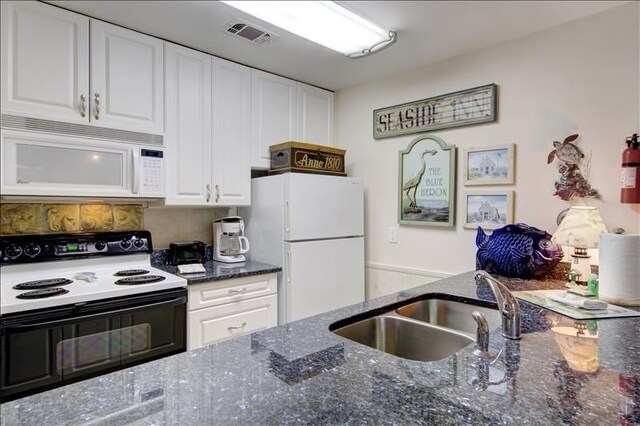 kitchen with sink, white appliances, white cabinetry, and dark stone countertops