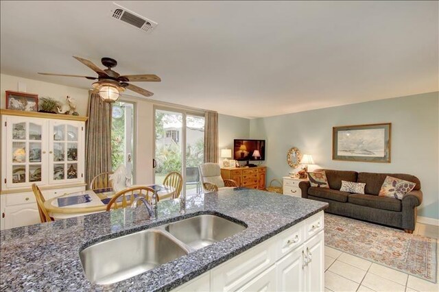 kitchen featuring dark stone countertops, white cabinetry, sink, and light tile patterned floors