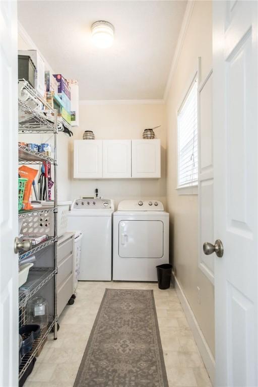 clothes washing area with cabinets, crown molding, and separate washer and dryer