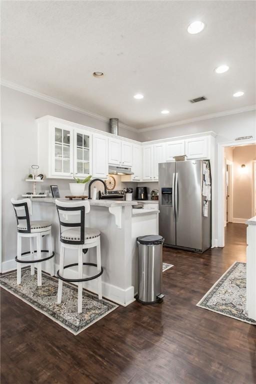 kitchen featuring a kitchen breakfast bar, dark hardwood / wood-style floors, ornamental molding, white cabinets, and stainless steel fridge with ice dispenser