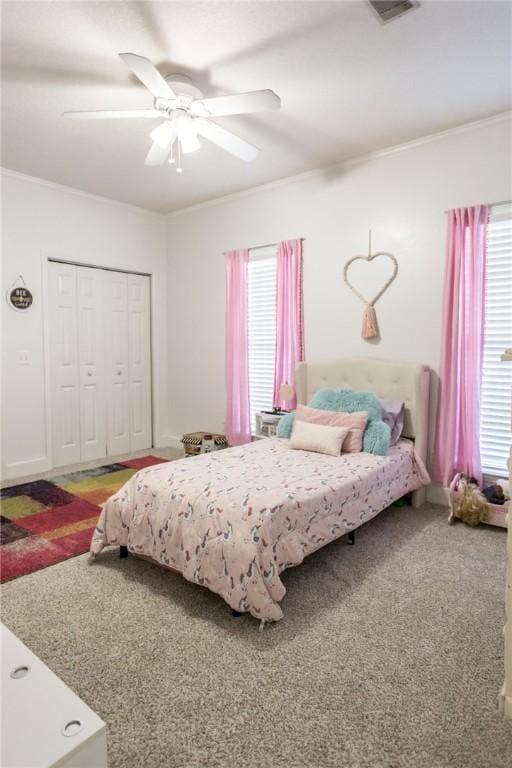 carpeted bedroom featuring ornamental molding, a closet, and ceiling fan