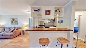 800 Mallery St Unit 3, Saint Simons Island, GA 31522 - kitchen with ornamental molding, a breakfast bar area, wood finished floors, and dark countertops