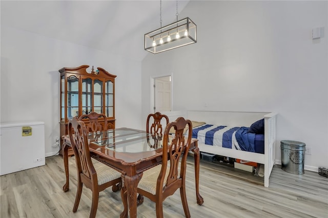 dining area with high vaulted ceiling and light wood-type flooring