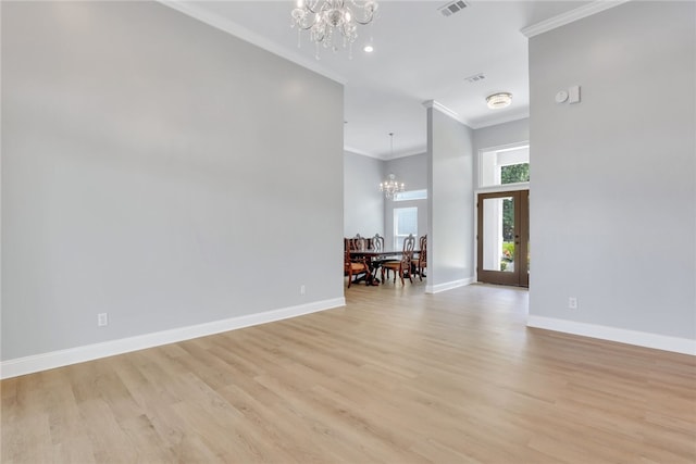 spare room with light wood-type flooring, crown molding, a high ceiling, and an inviting chandelier