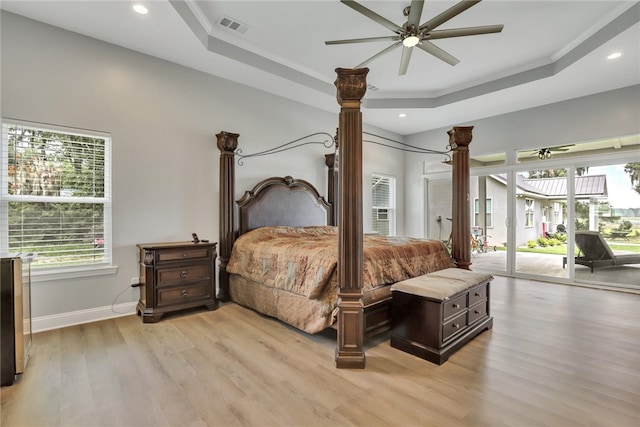 bedroom featuring access to outside, ceiling fan, a tray ceiling, and light hardwood / wood-style floors