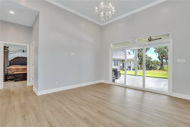 empty room featuring a high ceiling, light hardwood / wood-style flooring, crown molding, and a notable chandelier