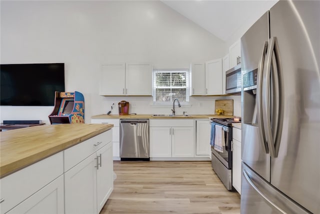 kitchen with appliances with stainless steel finishes, sink, light hardwood / wood-style flooring, white cabinetry, and lofted ceiling