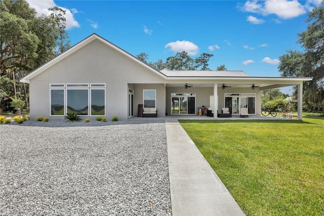 rear view of property featuring a lawn and ceiling fan