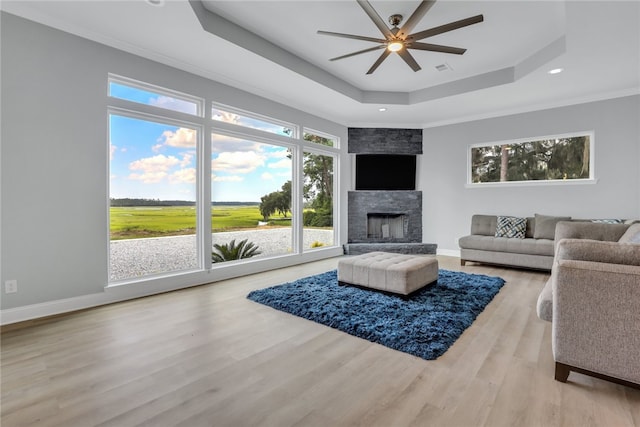 living room with hardwood / wood-style flooring, crown molding, ceiling fan, and a tray ceiling