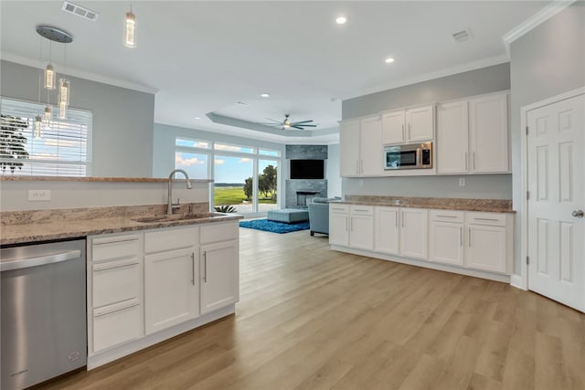 kitchen with stainless steel appliances, ceiling fan, sink, white cabinets, and light hardwood / wood-style floors