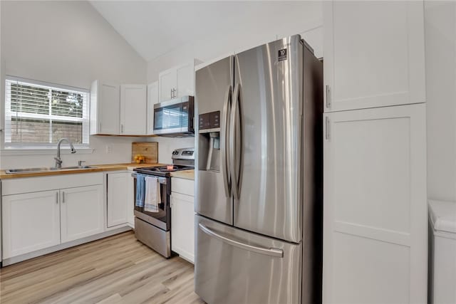 kitchen with white cabinets, appliances with stainless steel finishes, lofted ceiling, and sink