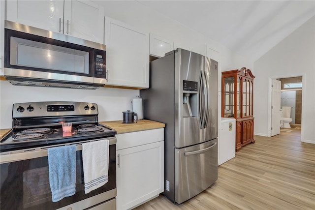 kitchen featuring wooden counters, appliances with stainless steel finishes, light wood-type flooring, vaulted ceiling, and white cabinets