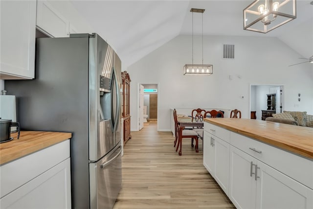 kitchen with stainless steel refrigerator with ice dispenser, light hardwood / wood-style flooring, white cabinetry, hanging light fixtures, and butcher block counters