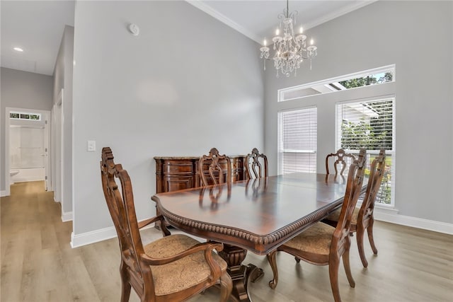 dining room with a high ceiling, light hardwood / wood-style floors, crown molding, and a notable chandelier