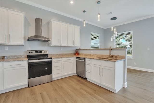 kitchen featuring wall chimney range hood, hanging light fixtures, sink, appliances with stainless steel finishes, and white cabinetry