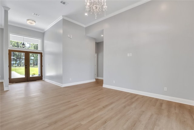 empty room featuring light hardwood / wood-style floors, an inviting chandelier, ornamental molding, and french doors