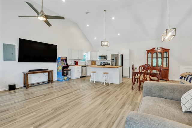 living room featuring ceiling fan, sink, high vaulted ceiling, light hardwood / wood-style flooring, and electric panel