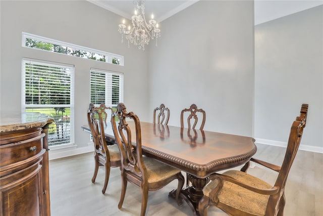 dining area with light wood-type flooring, ornamental molding, and an inviting chandelier