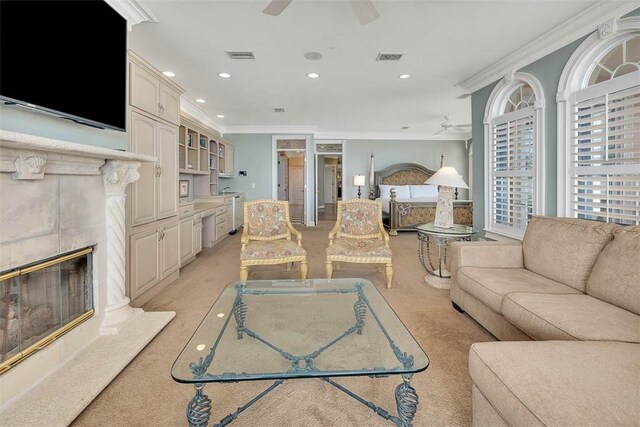 carpeted living room featuring ceiling fan, ornamental molding, and a tile fireplace