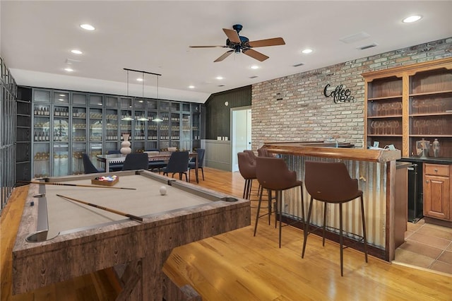 playroom featuring indoor bar, brick wall, and light hardwood / wood-style floors